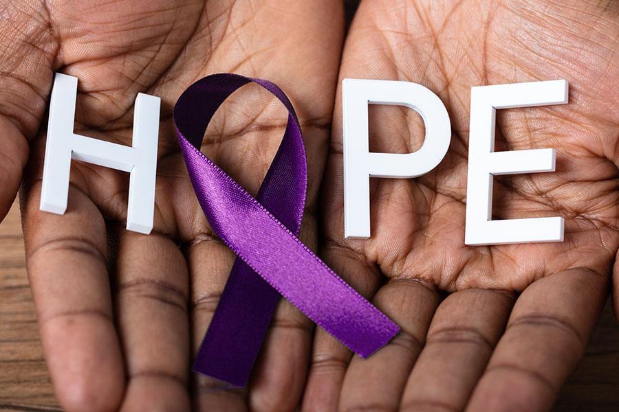 photo of hands holding a purple ribbon with the word "Hope"